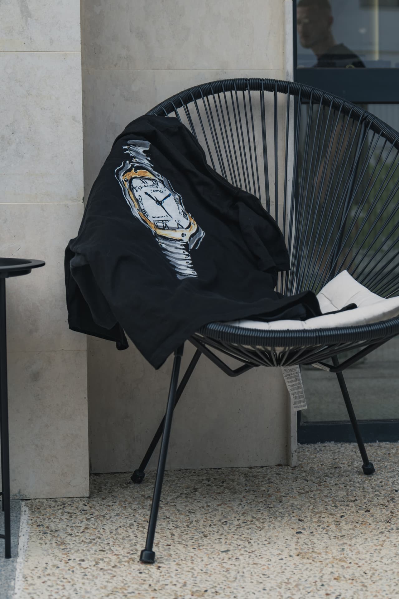 Hooded ATRIX garment draped over a chair, showing the melting-watch print
