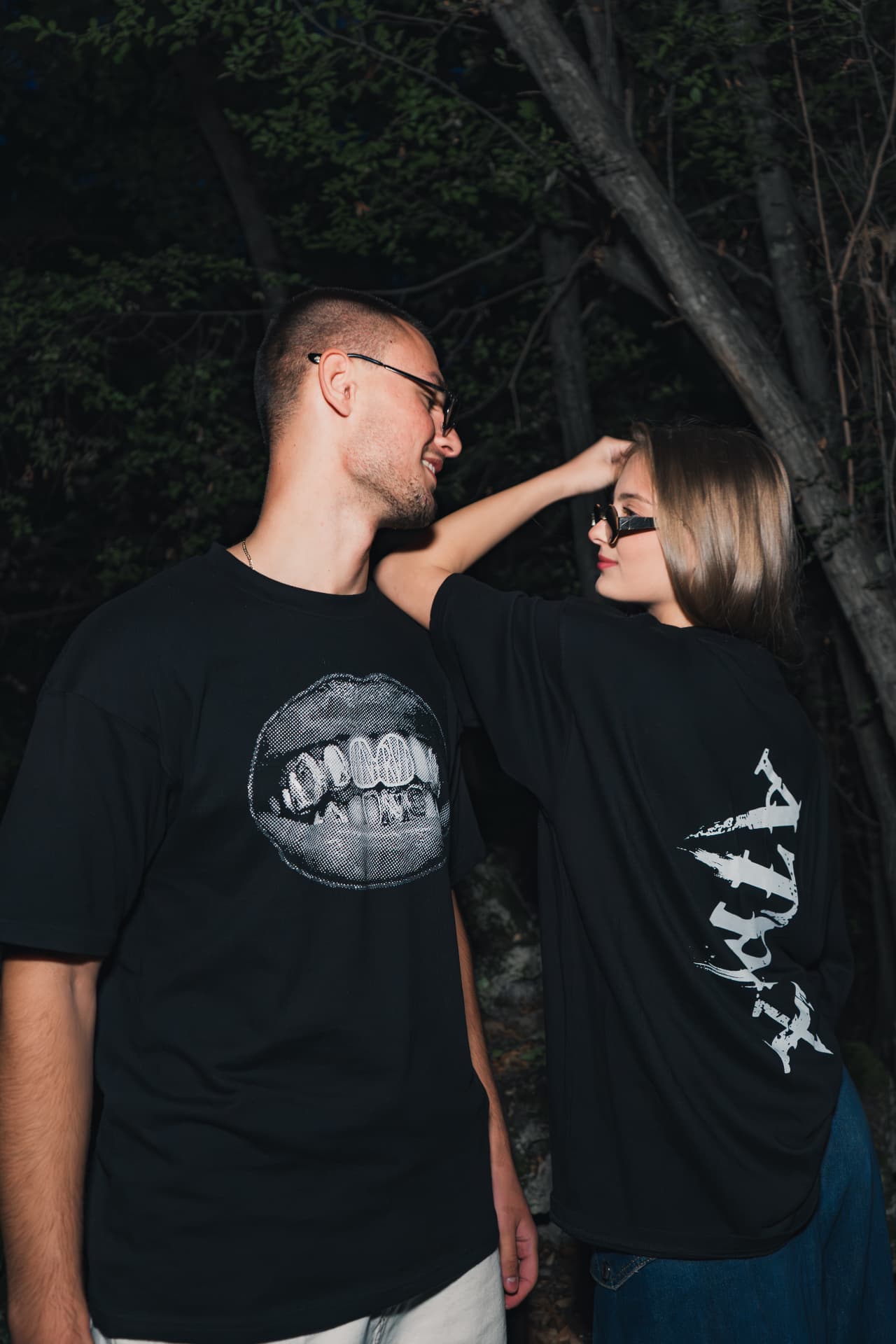Two people wearing ATRIX Drop 01 tees, flash-lit night portrait